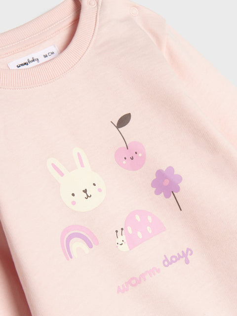 Pink sweatshirt with cartoon bunny, cherry, and flower design on a light gray background