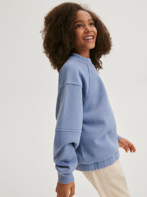Child wearing a blue sweatshirt against a white background