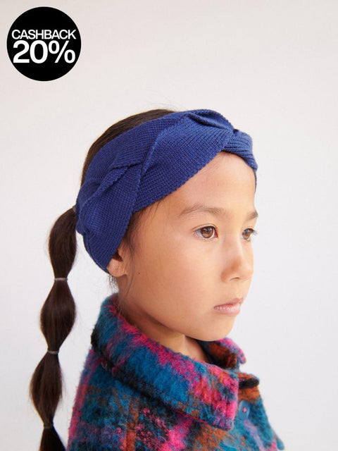 Child wearing a blue knitted headband with a plain background