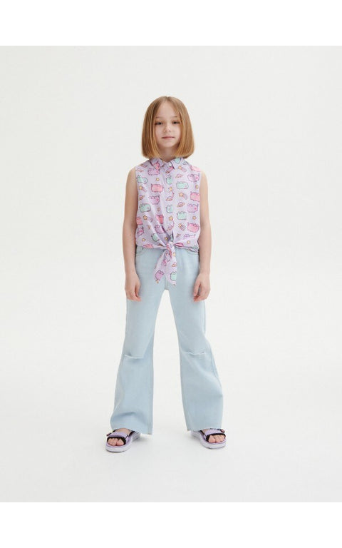 Young girl wearing a sleeveless top with text pattern and light blue jeans on a white background