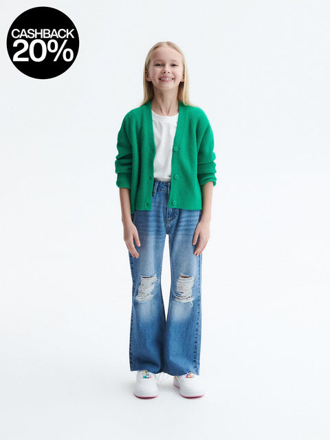 Person wearing a green cardigan, white shirt, and blue jeans on a white background with a cashback 20% offer.