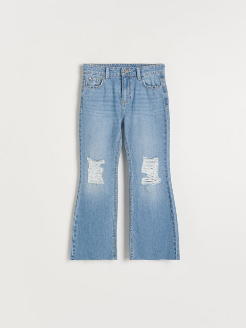 Blue jeans with distressed details on a white background
