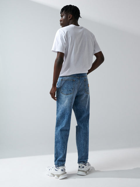 Person wearing a white t-shirt and blue jeans standing against a plain white background