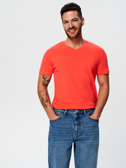 Man wearing a bright orange t-shirt and blue jeans on a white background