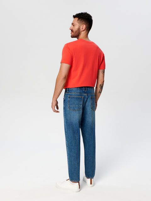 Man wearing a red shirt and blue jeans on a white background