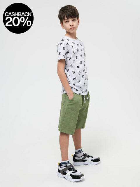 Child wearing a white t-shirt with black patterns and green shorts on a white background