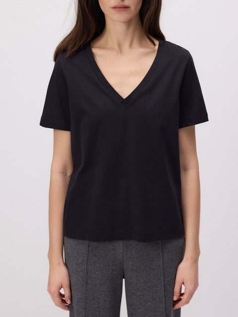 Person wearing a black V-neck t-shirt and gray pants on a white background