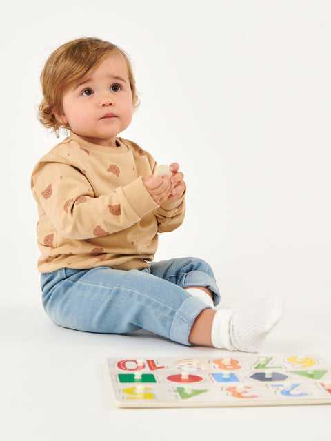Child sitting on a white surface with a colorful alphabet puzzle