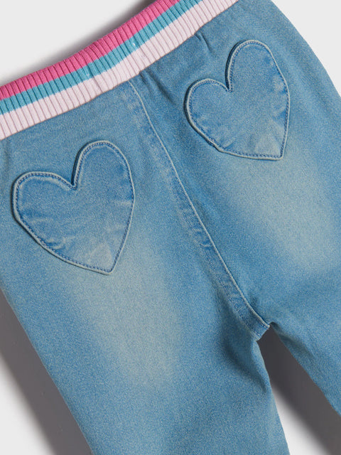 Blue denim pants with heart cutouts on a white background