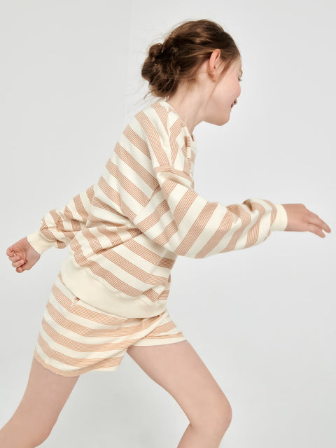 Person wearing a beige and white striped pajama set on a plain background