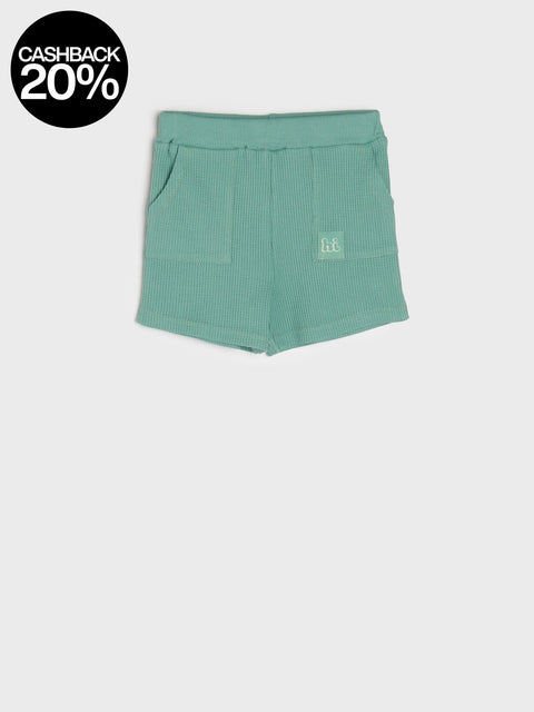 Green shorts with a small logo on a white background