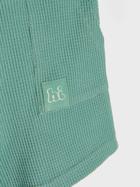 Green textured fabric with a small logo on a white background