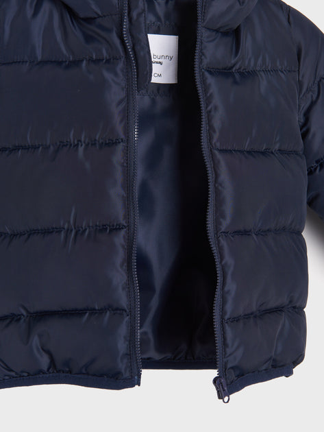 Navy blue puffer jacket with a brand label on a light gray background