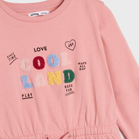 Pink children's outfit with colorful text and graphics on a white background