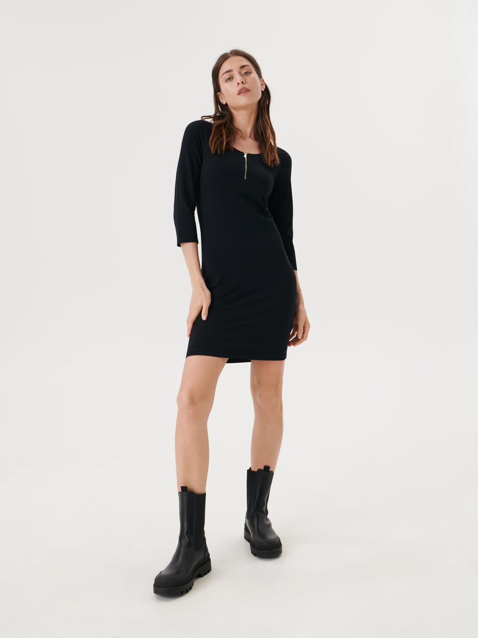 Woman wearing a black dress and black boots on a white background