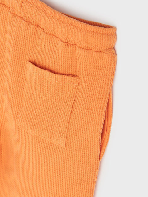 Close-up of orange textured pants on a white background