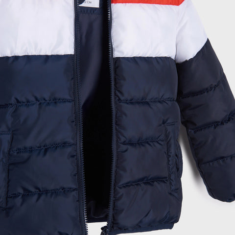 Close-up of a puffer jacket with navy, white, and red color block design on a light gray background.