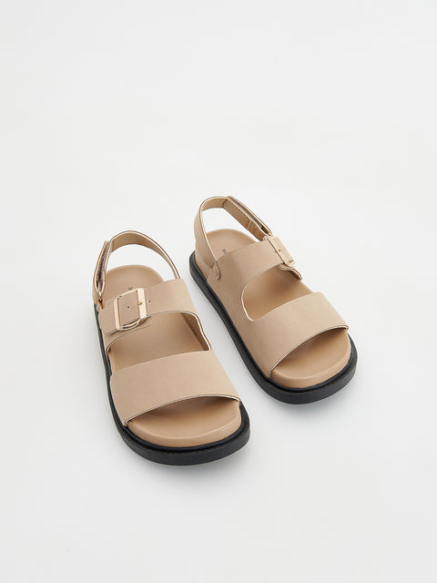 Pair of beige sandals with black soles on a light gray background