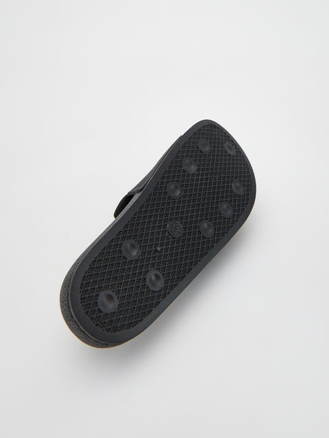 Black sandal sole with textured surface on a light gray background