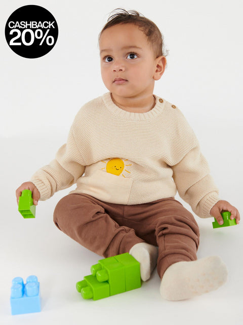 Baby sitting on a white surface with colorful building blocks
