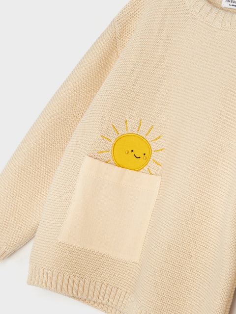 Beige sweater with a sun-shaped pocket on a white background