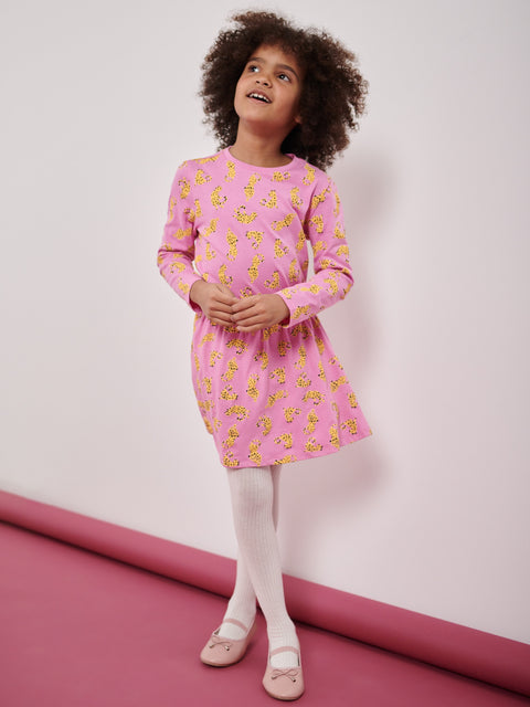 Young girl wearing a pink dress with yellow patterns on a white background