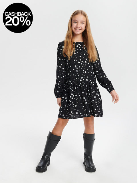 Young girl wearing a black dress with star pattern and black boots on a white background