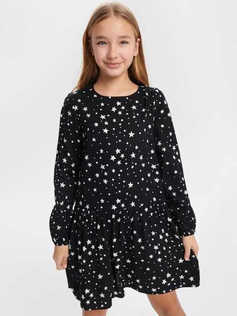 Young girl wearing a black dress with white star pattern on a white background