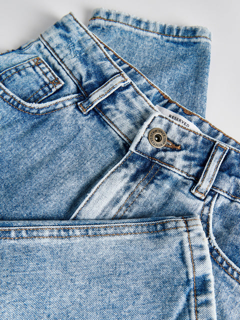 Close-up of a folded pair of blue jeans on a light background