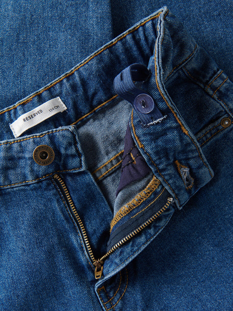 Close-up of a blue denim jacket with buttons and a brand label.