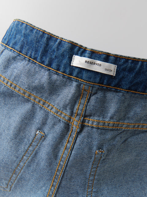 Close-up of blue denim fabric with a 'RESERVED' label on a white background