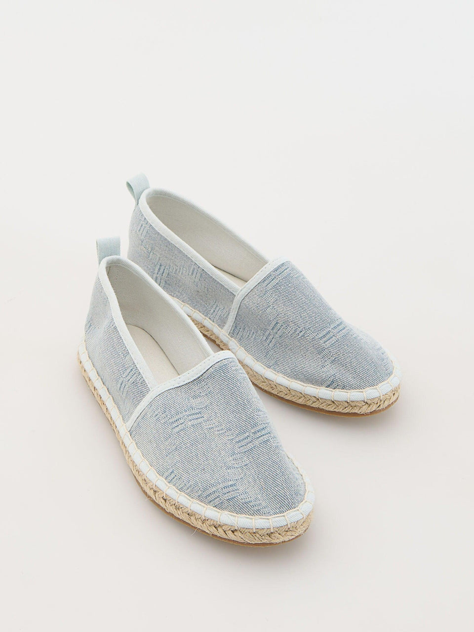 Pair of light blue espadrilles on a white background