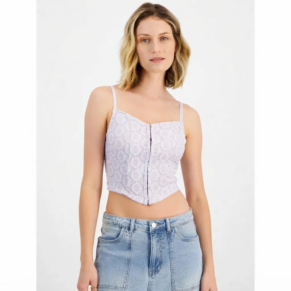 A woman modeling a light lavender lace camisole crop top with a front zipper and thin straps, paired with light-wash blue jeans against a plain white studio background.