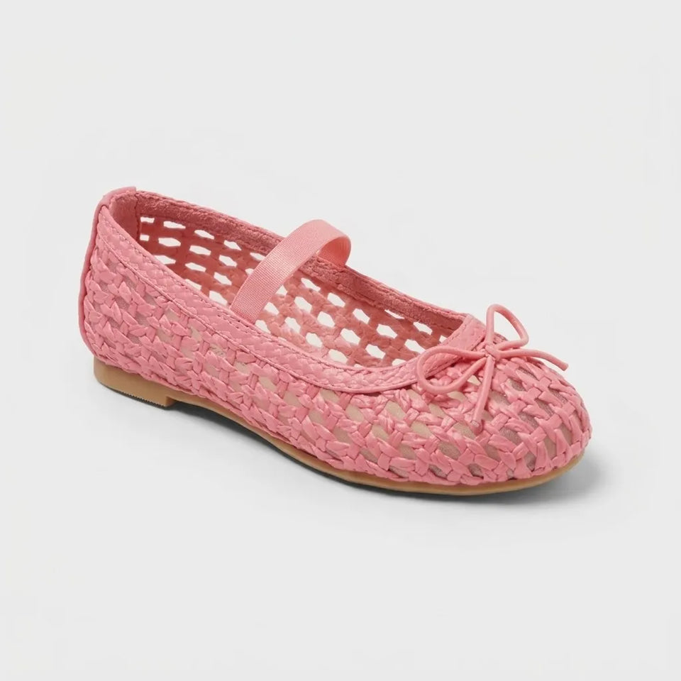 A pink woven openwork flat shoe with a Mary Jane strap and a matching bow on the toe, shown on a light gray background.