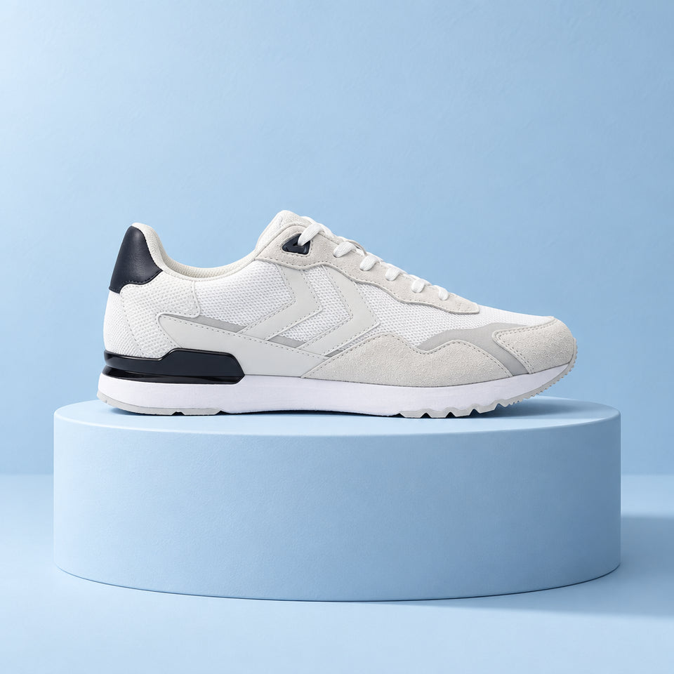 A low-top athletic sneaker in white and light gray suede and mesh, featuring black accents on the heel, tongue, and collar, shown from a side profile on a white background.