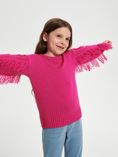 Young girl wearing a bright pink sweater with fringe details on a white background