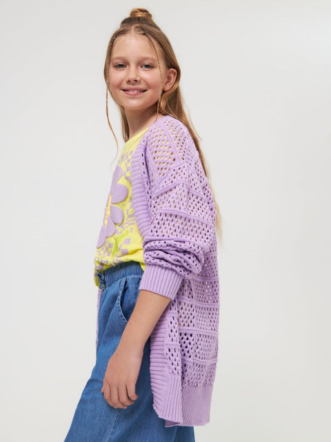 Young girl wearing a purple cardigan over a yellow shirt with a white background