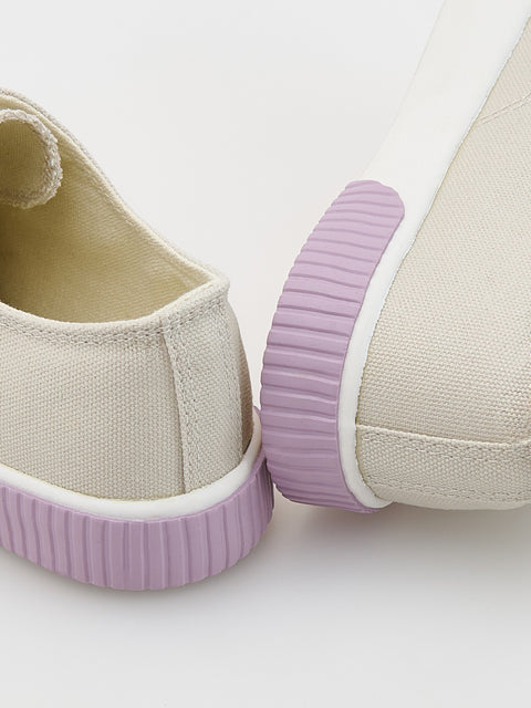 Beige canvas shoes with purple soles on a white background