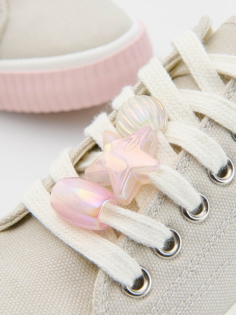Iridescent shoe clips on a beige sneaker with a pink bowl in the background