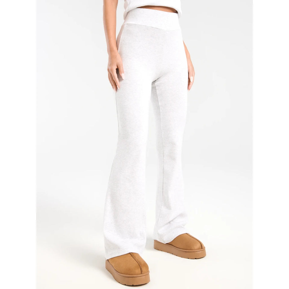 White high-waisted flared sweatpants worn by a model, paired with tan platform slippers against a plain white studio background.