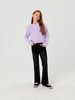 Person wearing a light purple sweater and black pants on a white background
