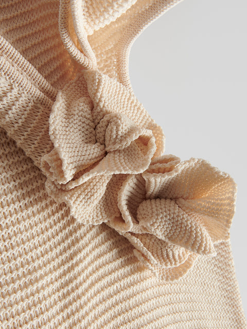 Close-up of a beige textured garment with ruffled details on a light background
