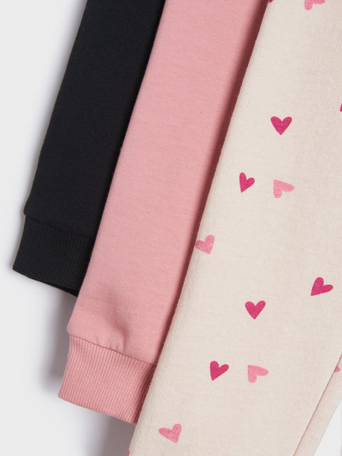 Three sweaters in black, pink, and beige with heart patterns on a white background