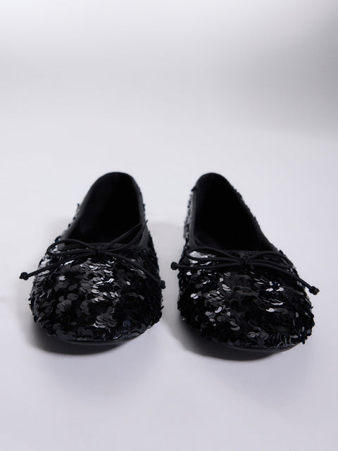 Pair of black sequin loafers on a white background