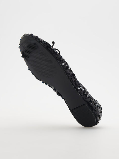 Black shoe with textured sole on a light gray background
