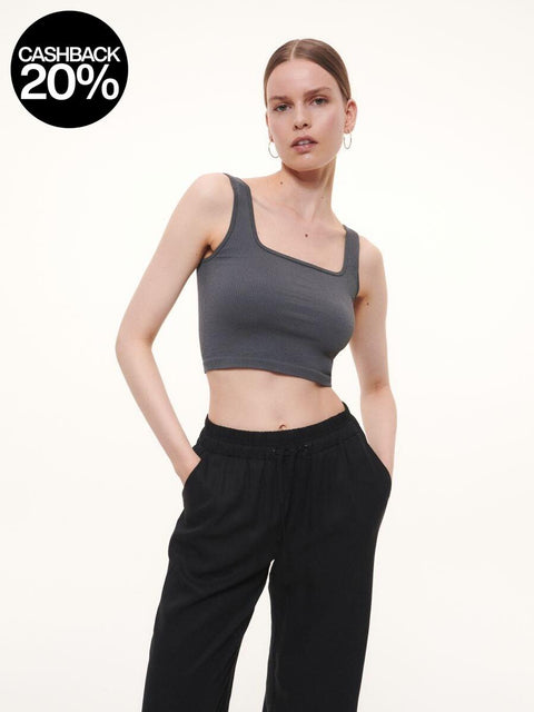 Woman wearing a gray tank top and black pants on a white background
