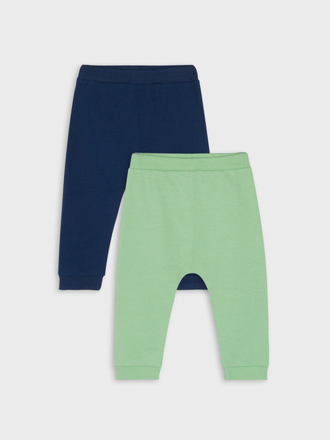 Two pairs of baby pants, one navy and one green, on a light gray background.