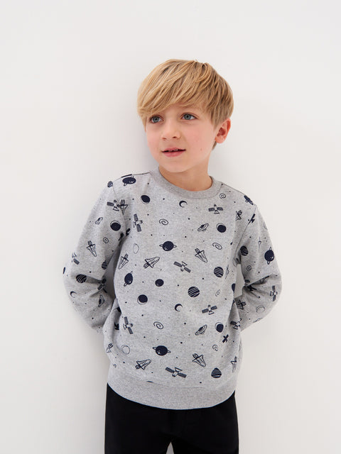 Young boy wearing a gray sweatshirt with space-themed patterns on a white background