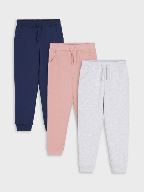 Three pairs of jogger pants in navy, pink, and gray on a white background