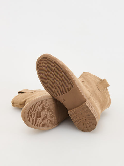 Pair of tan boots with soles facing up on a white background
